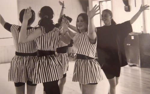 Old photo displaying a group of dancers in stripy costumes